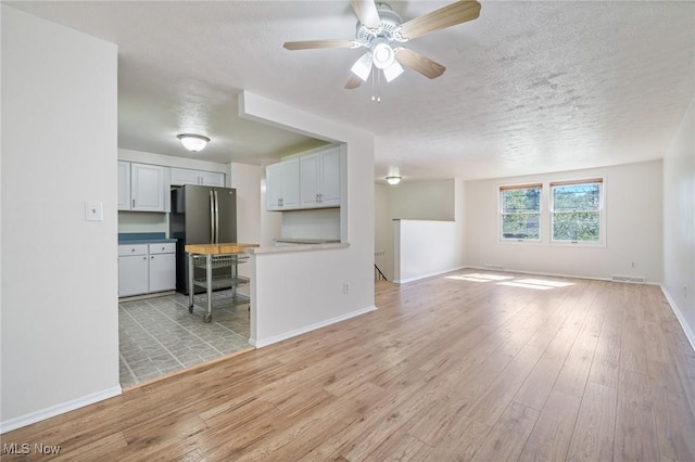 6414 Glenallen Ave, Solon, OH 44139 - unfurnished living room featuring a textured ceiling, light wood finished floors, ceiling fan, and baseboards