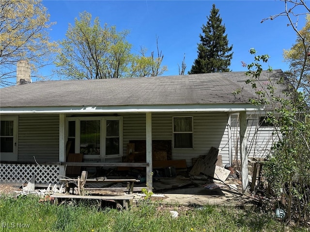 back of property with covered porch and a chimney