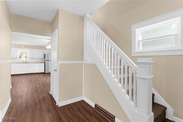 stairs with visible vents, a ceiling fan, baseboards, and wood finished floors