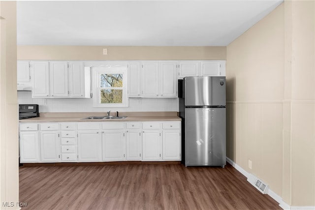 kitchen with visible vents, freestanding refrigerator, dark wood-style floors, white cabinetry, and a sink