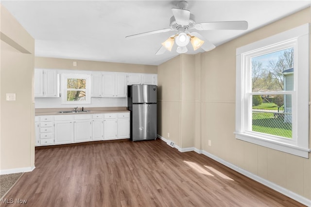kitchen with dark wood finished floors, baseboards, freestanding refrigerator, white cabinetry, and a wealth of natural light