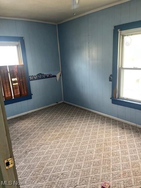 empty room featuring baseboards, plenty of natural light, ornamental molding, and carpet