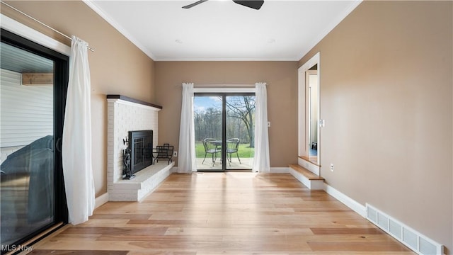 unfurnished living room featuring crown molding, ceiling fan, light wood finished floors, a fireplace, and visible vents