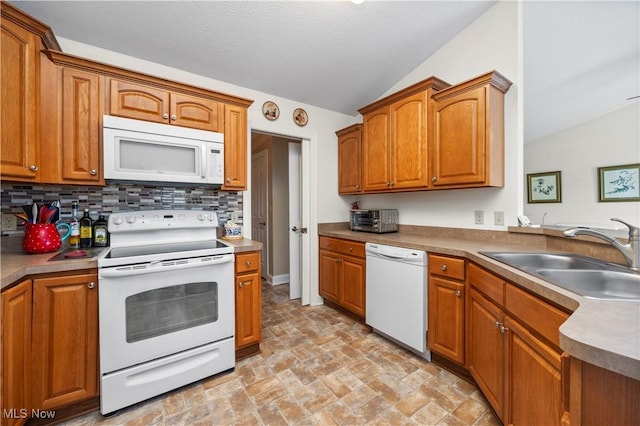 kitchen featuring brown cabinetry, white appliances, a sink, backsplash, and vaulted ceiling