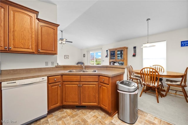 kitchen featuring brown cabinetry, a peninsula, ceiling fan, a sink, and dishwasher