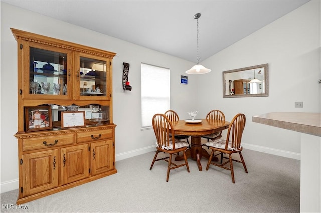 dining room with baseboards, lofted ceiling, and light colored carpet