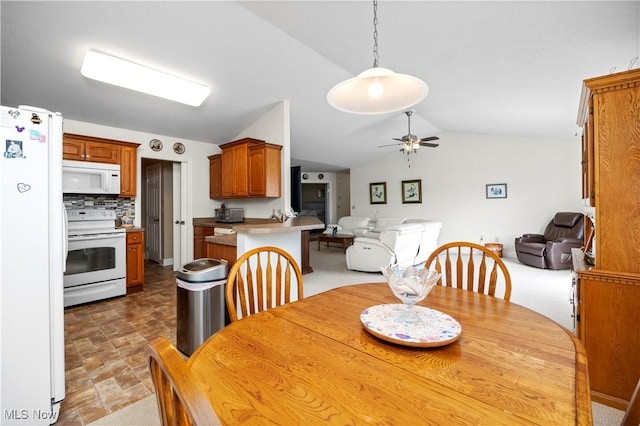 dining area featuring stone finish flooring, ceiling fan, and vaulted ceiling
