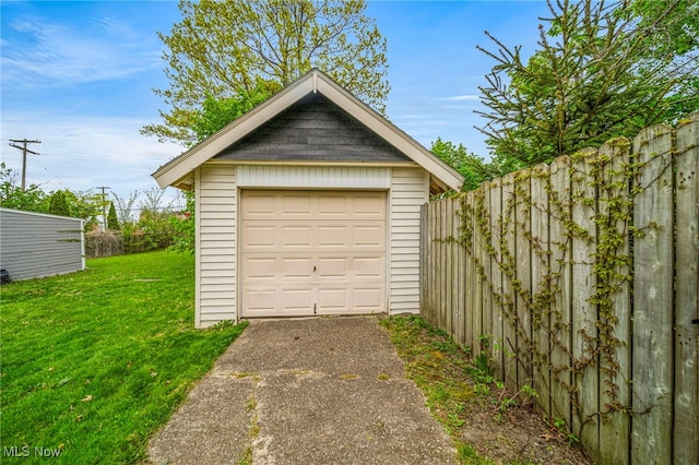 detached garage featuring fence and driveway