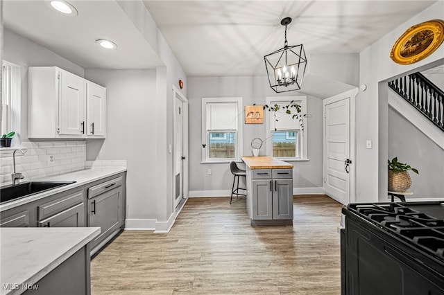 kitchen featuring baseboards, gray cabinetry, a sink, and light wood-style flooring