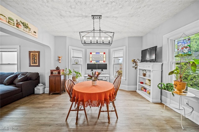 dining space with a textured ceiling, a notable chandelier, a wealth of natural light, and light wood finished floors