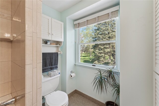 bathroom featuring tile patterned flooring, baseboards, a wealth of natural light, and toilet