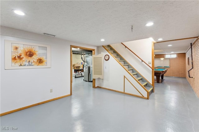 below grade area featuring stairs, brick wall, recessed lighting, a textured ceiling, and pool table