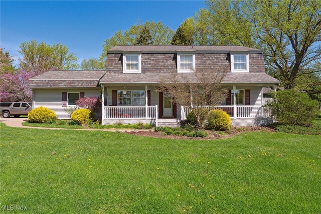traditional-style home with roof with shingles, covered porch, and a front yard