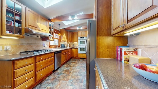 431 Somerset Dr, Chagrin Falls, OH 44022 - kitchen with brown cabinetry, under cabinet range hood, vaulted ceiling with skylight, a sink, and appliances with stainless steel finishes