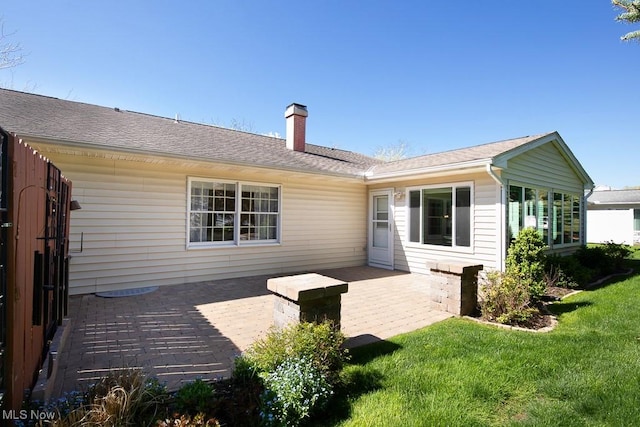back of property with a lawn, a chimney, and roof with shingles