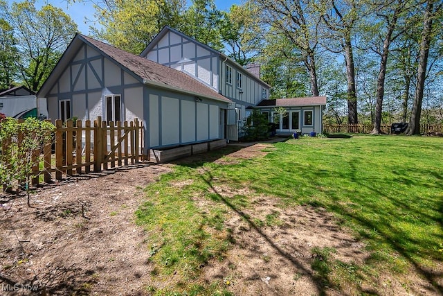 back of house with a lawn, fence, and board and batten siding