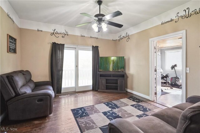 living area featuring baseboards, a ceiling fan, and wood finished floors