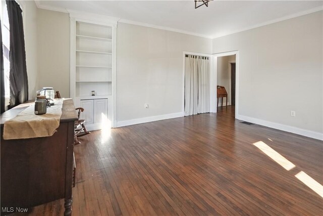 office area with built in features, baseboards, dark wood-type flooring, visible vents, and ornamental molding