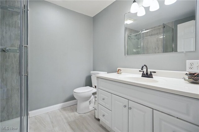 bathroom featuring vanity, toilet, baseboards, and a stall shower