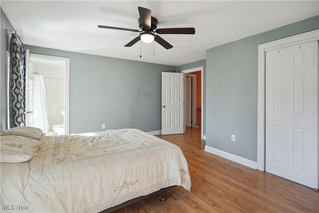 bedroom featuring baseboards, ensuite bathroom, a ceiling fan, and wood finished floors