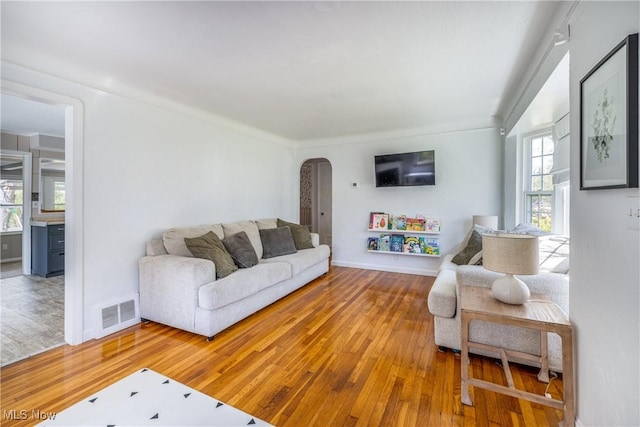 living area featuring visible vents, arched walkways, baseboards, and hardwood / wood-style flooring