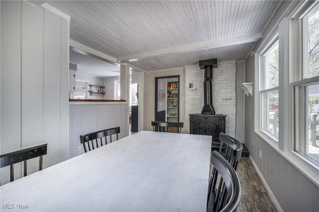 interior space featuring beamed ceiling, a wood stove, and wood finished floors
