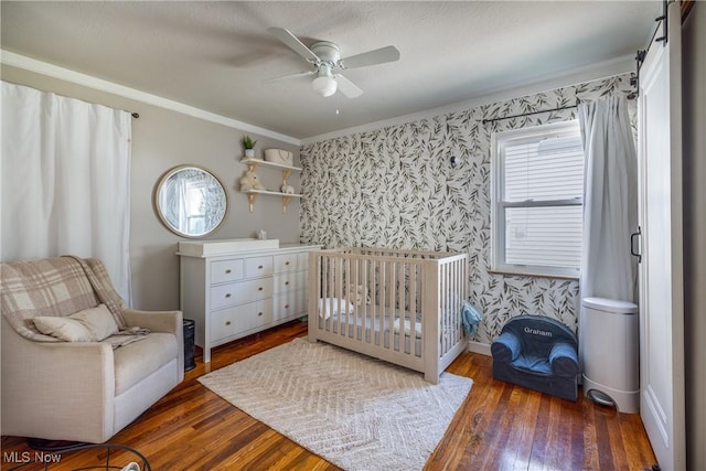 bedroom featuring wallpapered walls, multiple windows, and hardwood / wood-style flooring