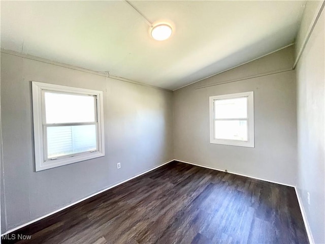 spare room with baseboards, dark wood finished floors, and vaulted ceiling