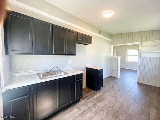 kitchen with light wood-type flooring, a sink, baseboards, and light countertops