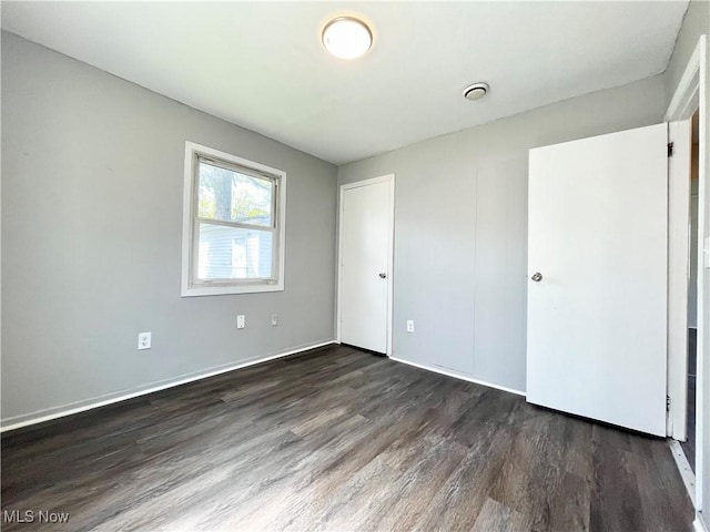 unfurnished bedroom with baseboards, dark wood-style flooring, and visible vents