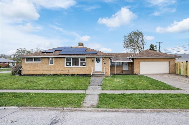 single story home featuring a garage, a front lawn, fence, concrete driveway, and solar panels