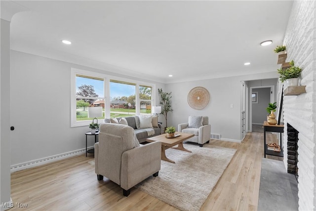 living area with a fireplace, recessed lighting, baseboards, and light wood-style floors