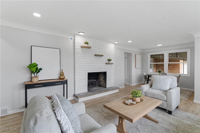 living room featuring baseboards, recessed lighting, light wood finished floors, and a fireplace