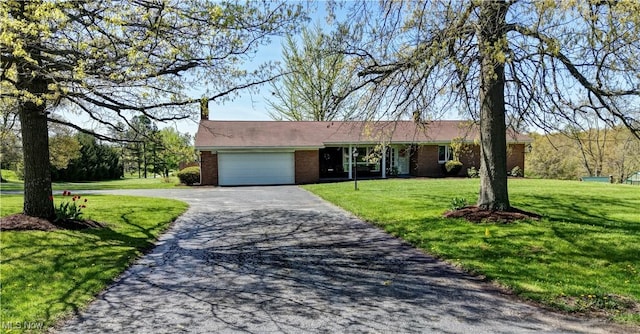 ranch-style house featuring a garage, a front yard, brick siding, and aphalt driveway