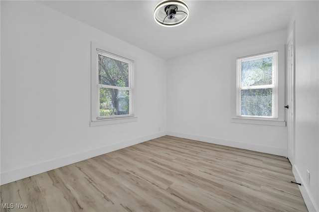 empty room with baseboards, light wood-style flooring, and a wealth of natural light