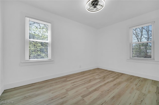 unfurnished room with baseboards and light wood-type flooring