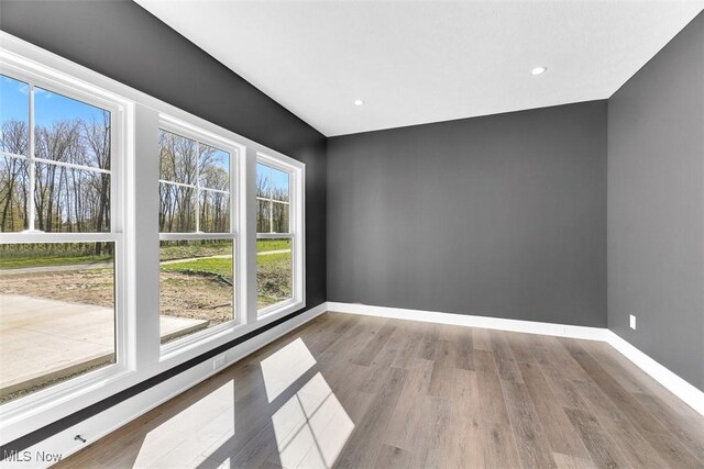 spare room with baseboards, recessed lighting, and wood finished floors