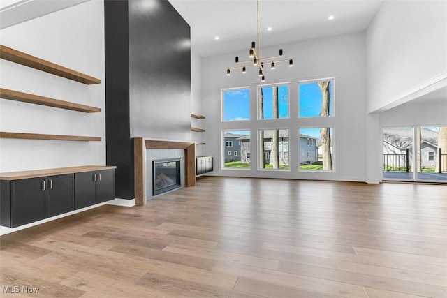 unfurnished living room featuring recessed lighting, a high ceiling, light wood-type flooring, and a fireplace