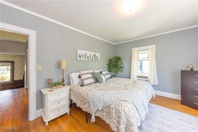 bedroom featuring multiple windows, ornamental molding, and light wood-style flooring