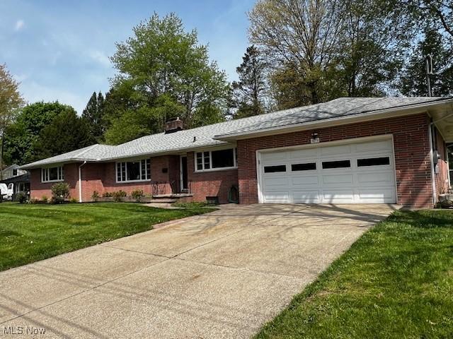 ranch-style house with an attached garage, brick siding, a front yard, a chimney, and concrete driveway