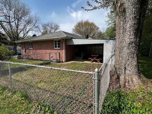 view of side of home featuring brick siding, a yard, and fence private yard
