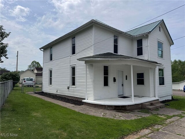 view of front of house featuring fence, covered porch, metal roof, and a front yard