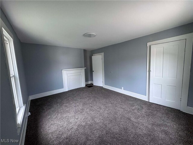 unfurnished bedroom featuring baseboards and dark colored carpet