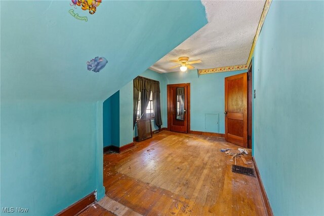 interior space featuring wood-type flooring, a textured ceiling, baseboards, and ceiling fan