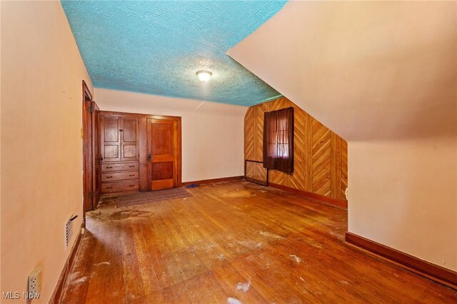 bonus room featuring baseboards, a textured ceiling, and hardwood / wood-style floors