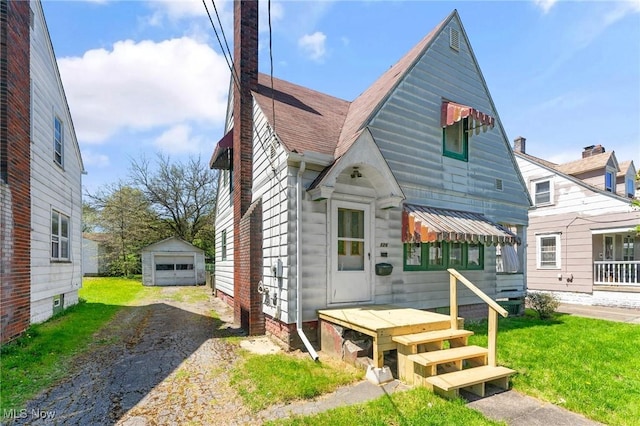 view of front of house featuring driveway, a front lawn, an outdoor structure, and a garage