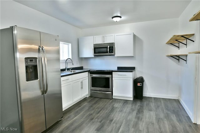1553 Parkman Rd NW, Warren, OH 44485 - kitchen featuring dark countertops, dark wood-type flooring, white cabinetry, a sink, and appliances with stainless steel finishes