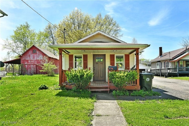 bungalow-style house featuring a barn, an outdoor structure, a porch, and a front yard