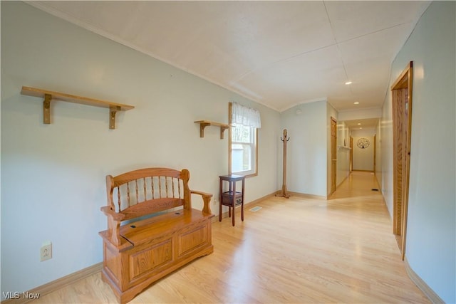 living area with light wood-style floors, baseboards, and ornamental molding