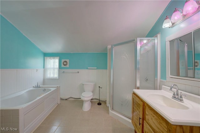 bathroom with tile patterned flooring, wainscoting, vaulted ceiling, and a shower stall